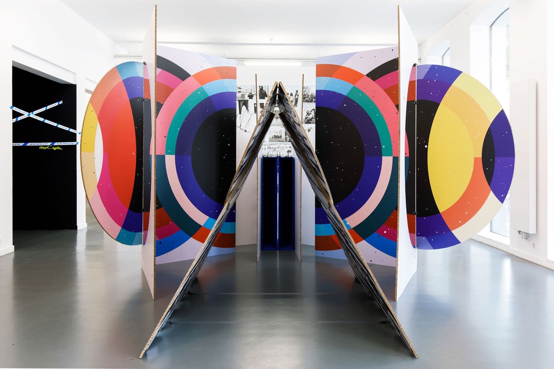 City of Sun Tent in Rotterdam. The installation consists of white cardboard panels covered in brightly coloured concentric circles and black and white photos.