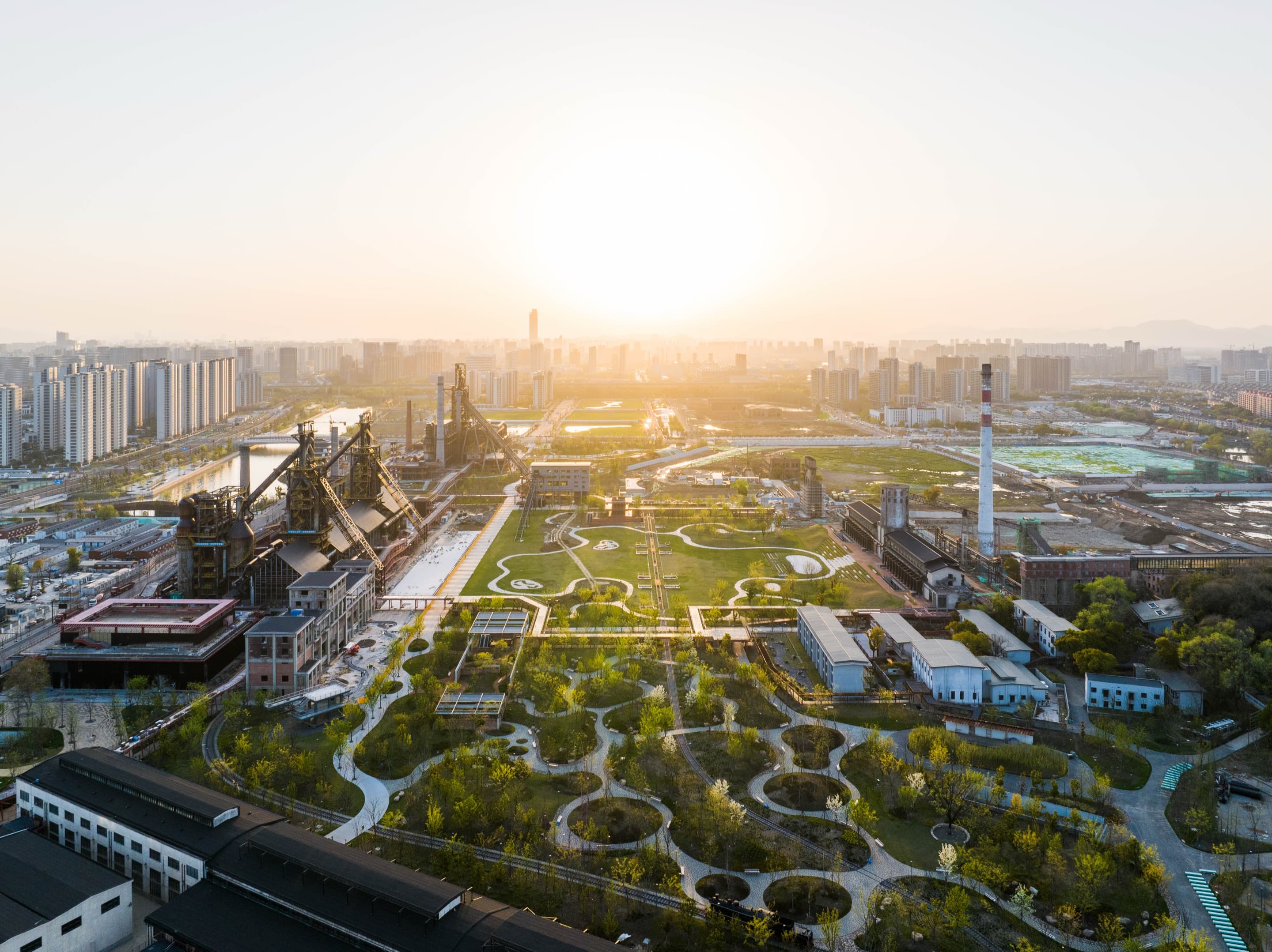Aerial view over a landscaped former steelworks at sunset.