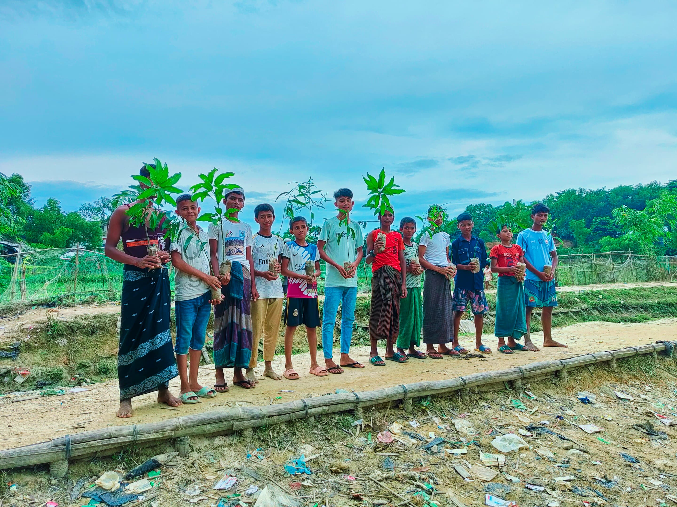 Mohammed Answer stands in the middle of a line of young people holding tree saplings.