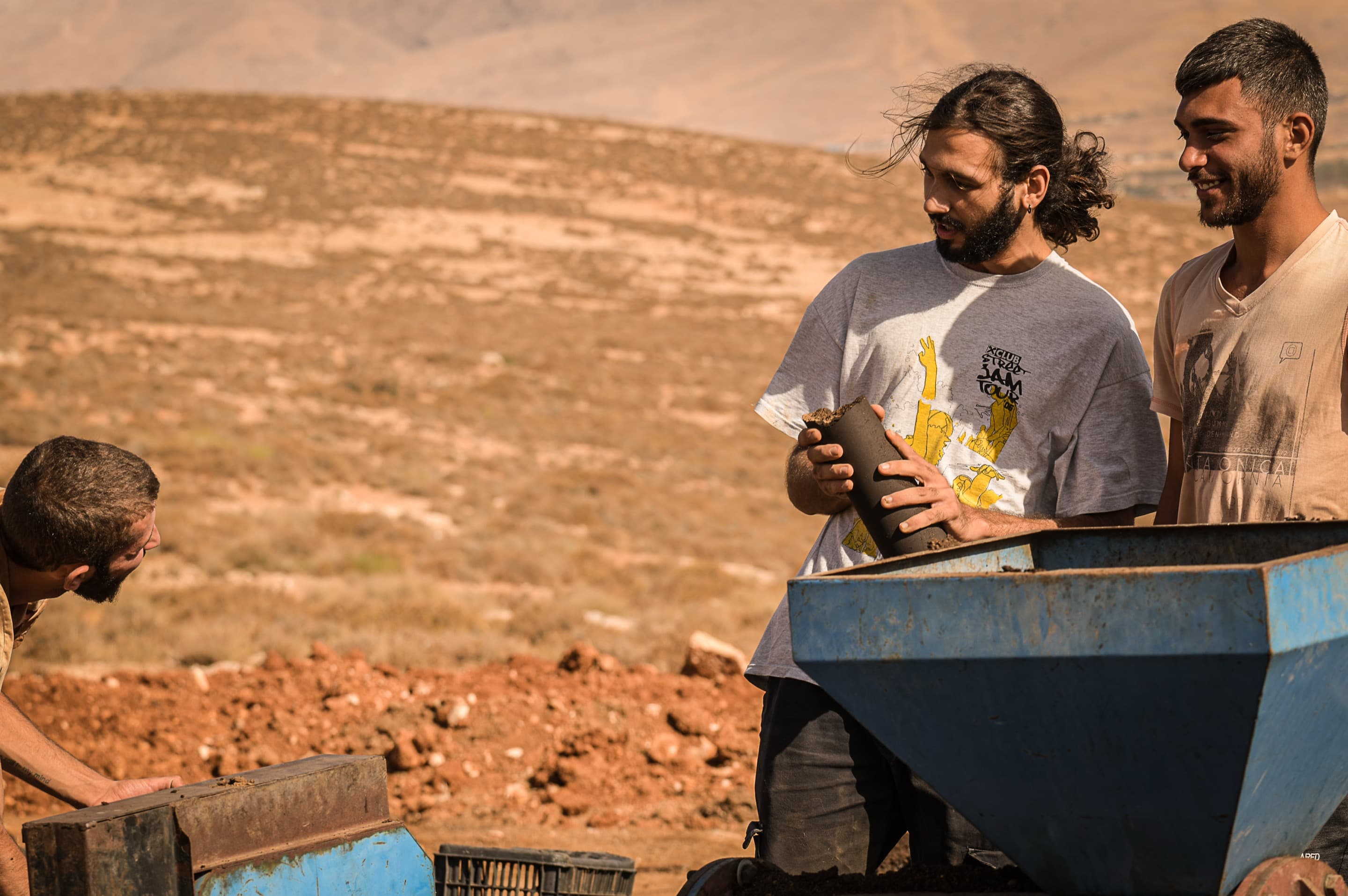 Carlos Ayvazian talks to a team member while holding a log-sized, brown pellet.