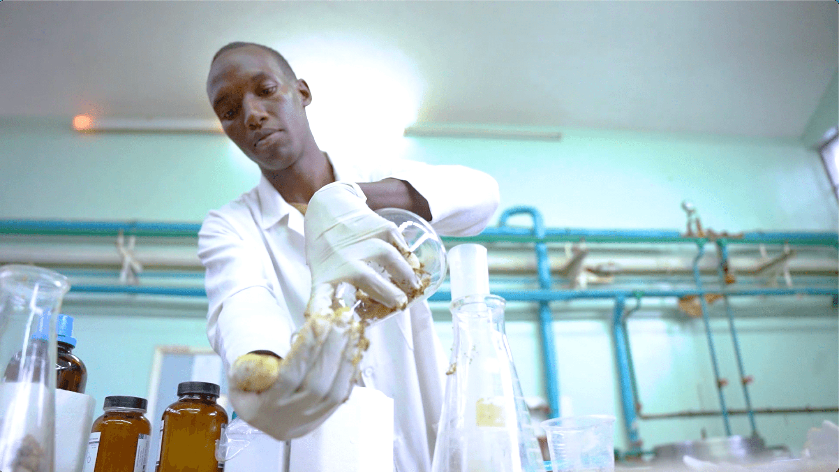 Joseph Nguthiru pours out the contents of a test tube in a brightly lit lab.