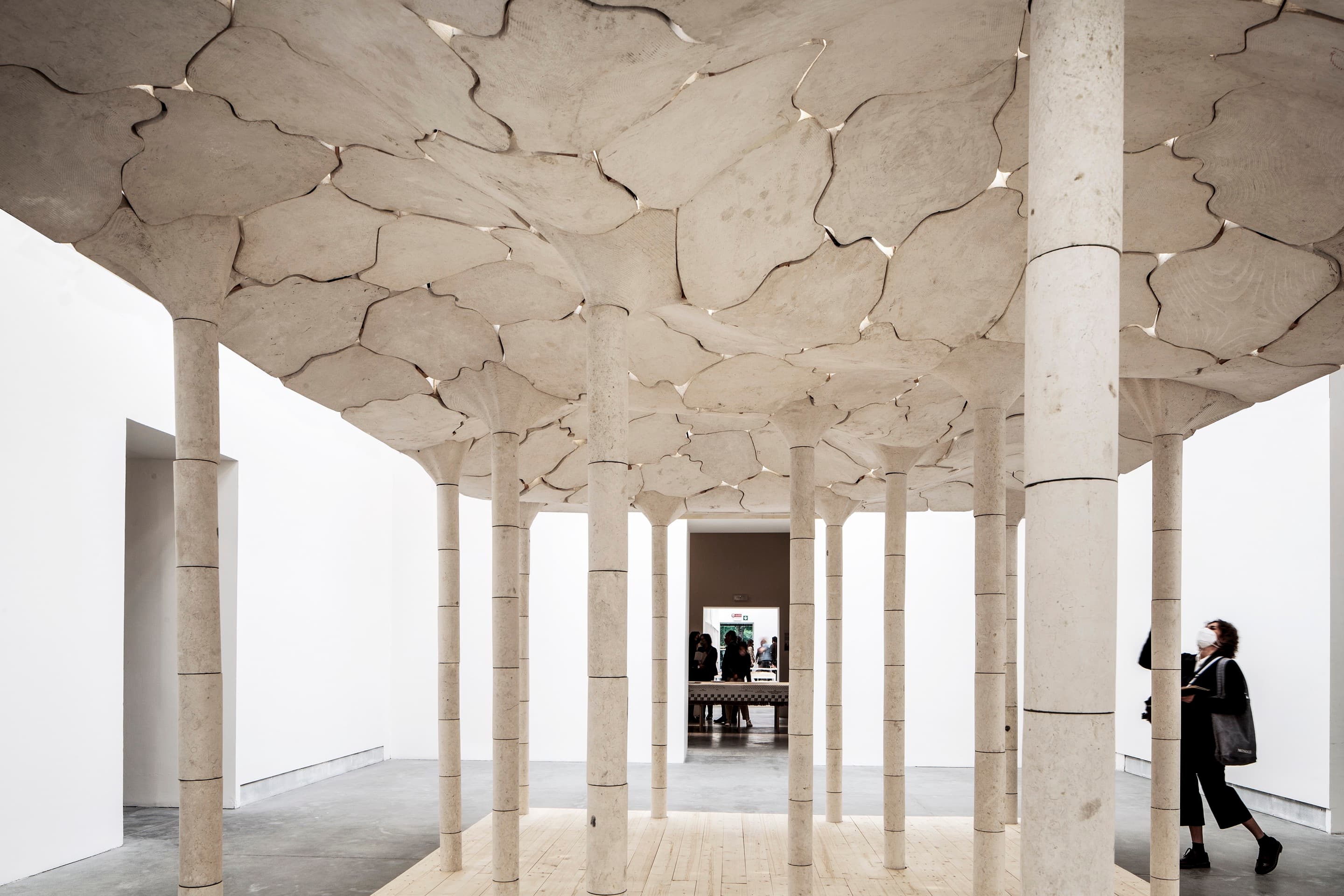 All-Purpose Pavilion at the 2023 Venice Biennale. The roof of the pavilion is formed of white tessellating stone pieces and supported by slender cylindrical stone columns.