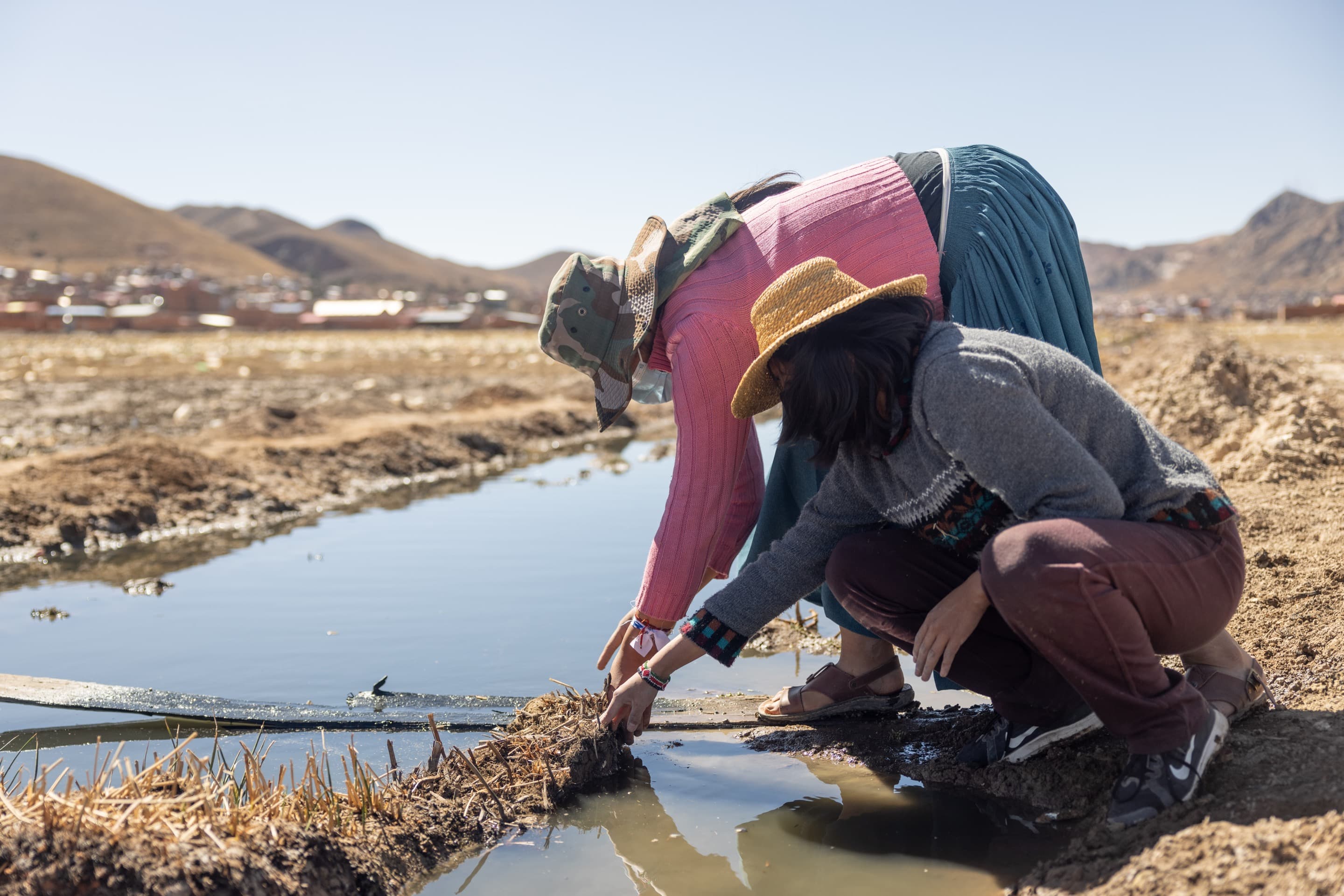 Dayana Blanco Quiroga kneels to examine the water at Lake Uru Uru.