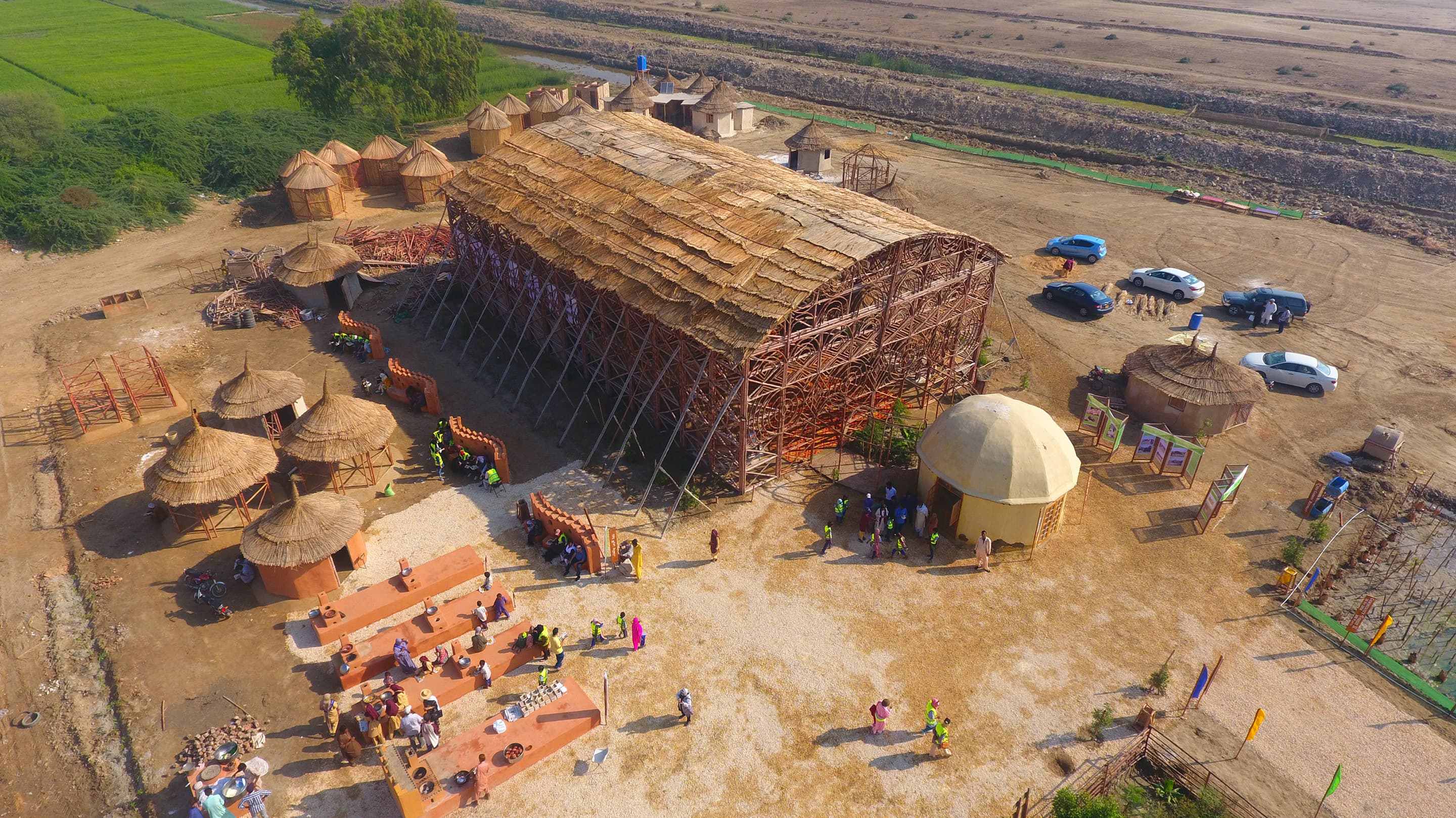 Aerial view of Zero Carbon Culture Center near Makli, Pakistan. The form of the bamboo building resembles a hangar. It has a barrel-vaulted roof and ornamented walls.